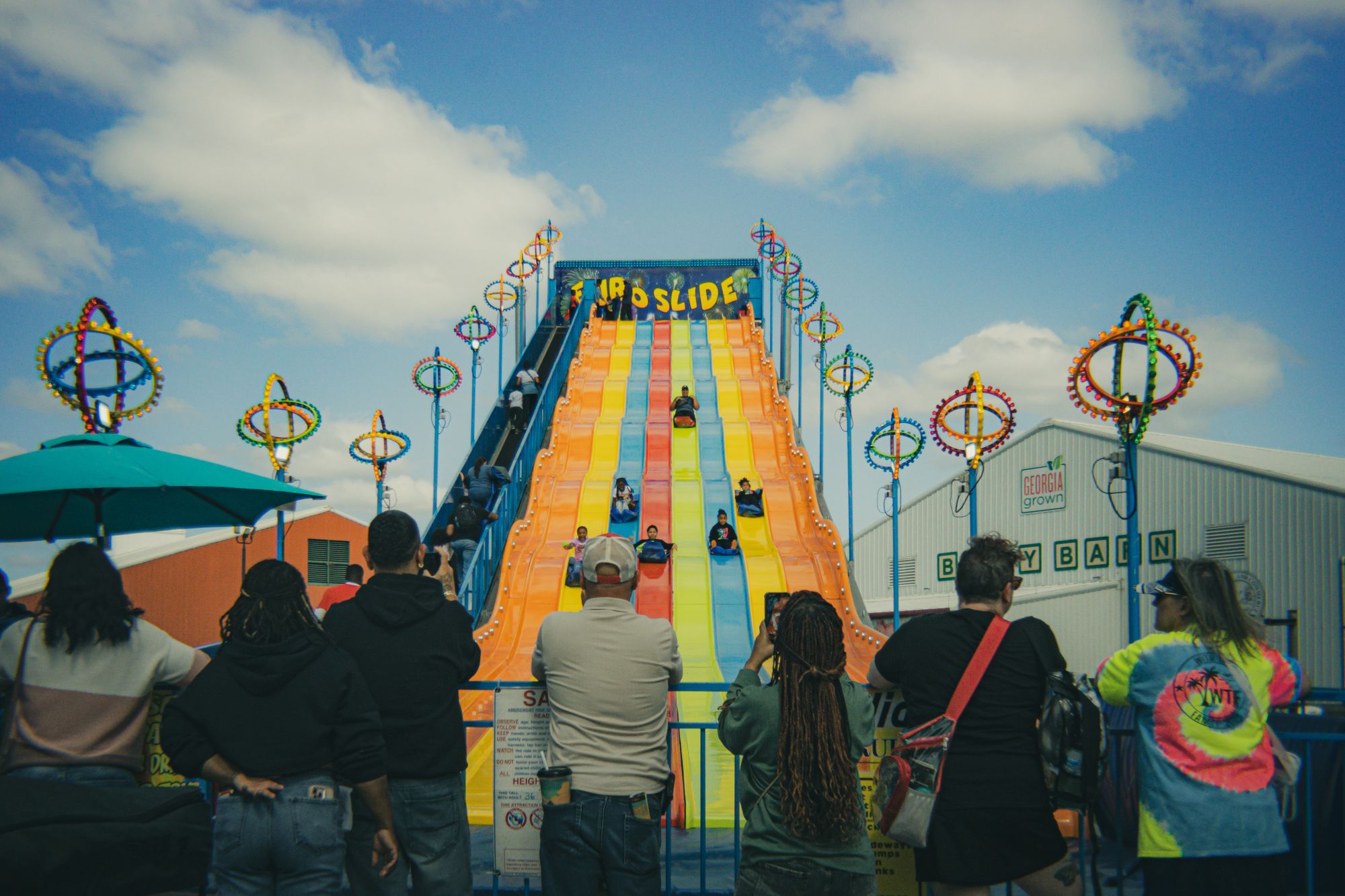 A crowd lining up for a giant inflatable slide at a community event