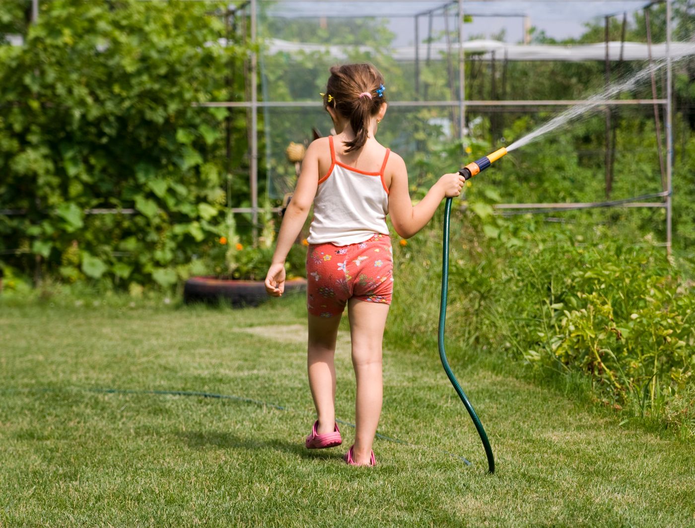 Girl playing with a hose in the garden