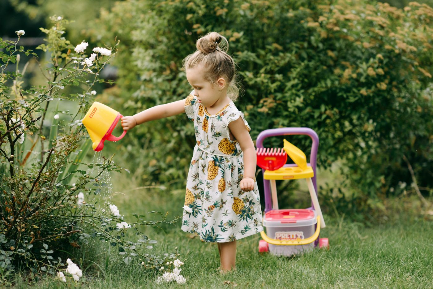 Toddler watering plants in a backyard